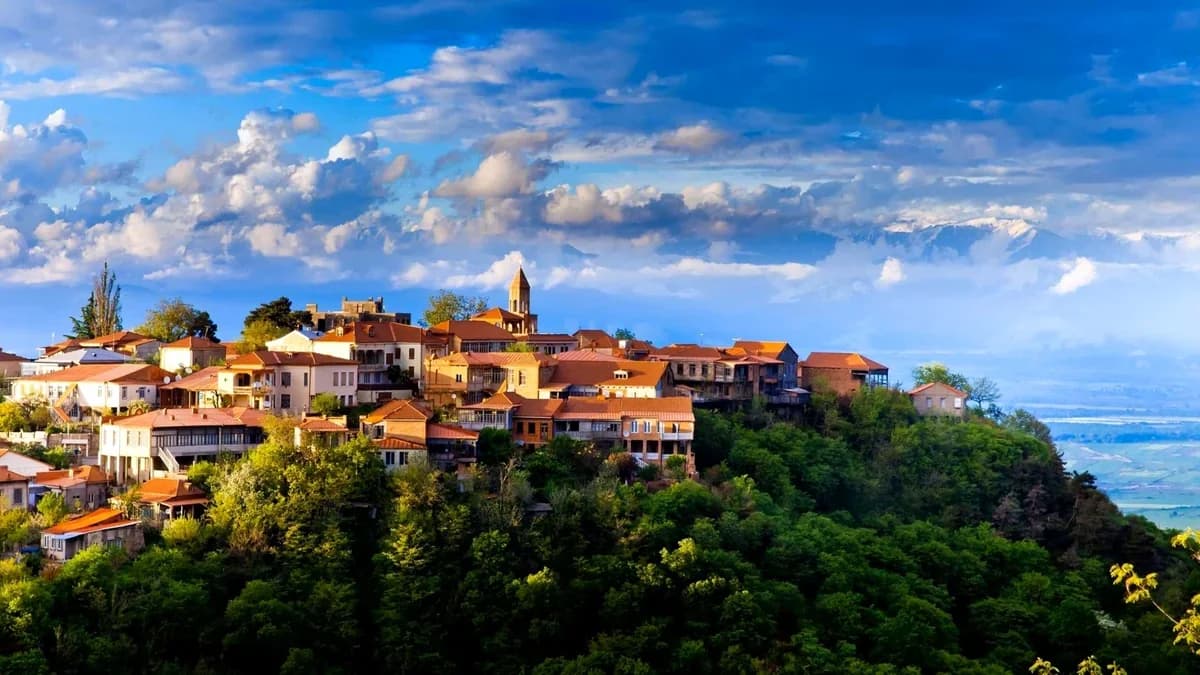 Sighnaghi's town walls and rooftops above the Alazani Valley with the Caucasus behind